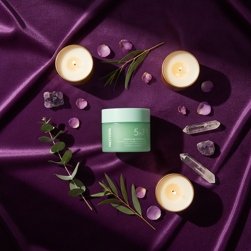 Overhead flat lay of 5 In 1 Arbutin Cream with spa elements and purple gold styling